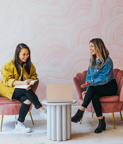 Two girls sitting and collaborating with a laptop