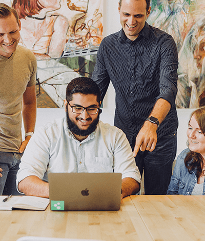 A small group of people huddled over a laptop