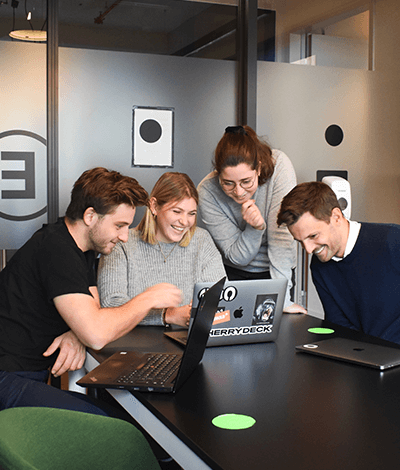 People bent over a computer screen smiling