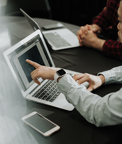 Photo of someone's arm pointing to information on a laptop screen