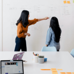 Two people pointing on a whiteboard