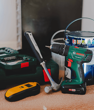 Tools and renovation hardware including a drill, paint can, hammer.