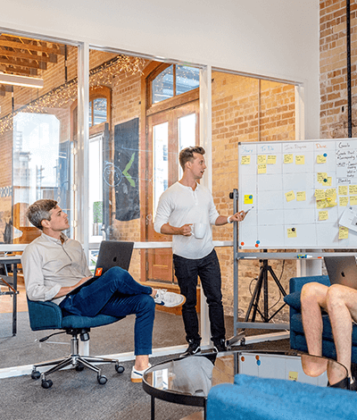 Two people standing next to a whiteboard and brainstorming business ideas